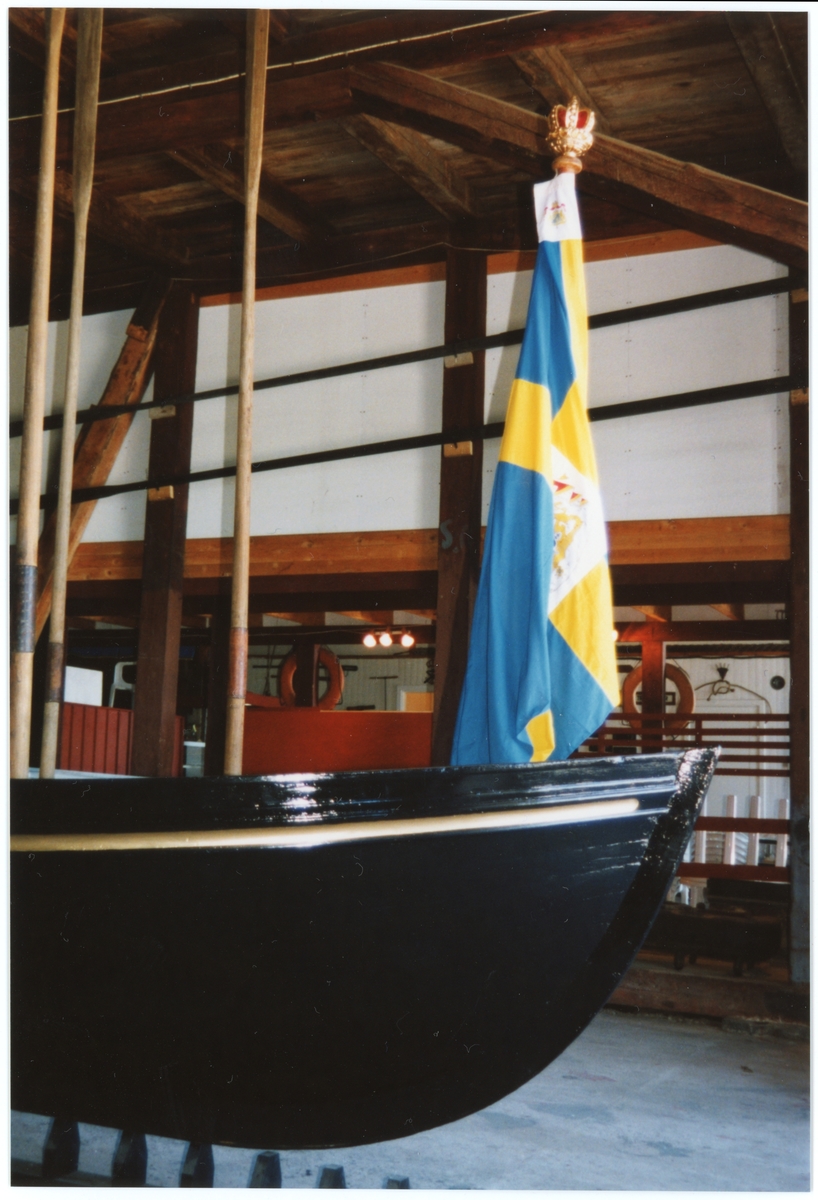 Bilden visar kungaslupens nr 44 förstäv med uppställda åror och svensk flagga från styrbordsidan.