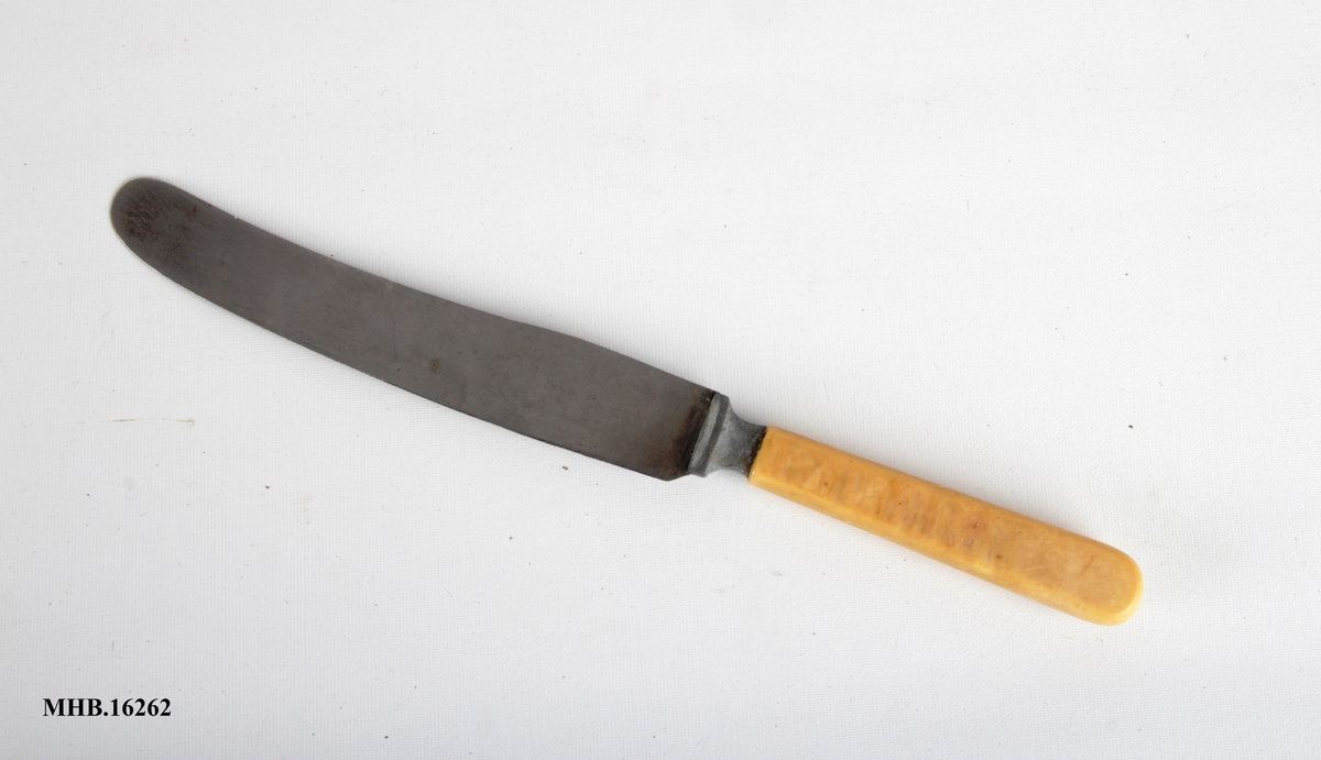 Bordkniv med avrundet blad og hvitt plastskaft.