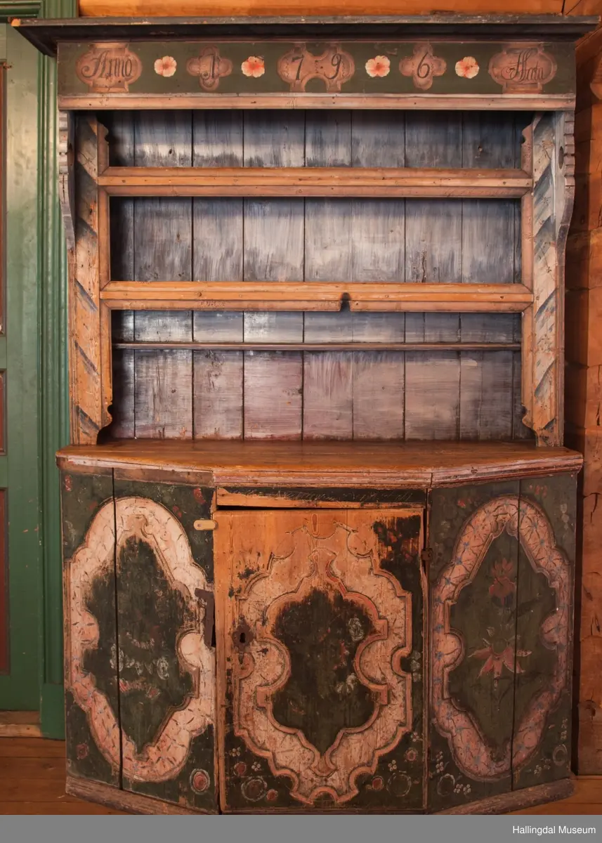 Marmorert toppstykke over felt med fem fyllinger.  Feltet grønnmalt med røde og hvite blomster.  Fyllingene, hvit bunn, sortmalte bokstaver og tall:  Anno 1796 H. Sata.  Overskapet har to hyller med lister og en smal hylle med profilert kant.  Bakveggen hvitmalt med rester etter mørkere undermaling, sideveggene marmorert.  Underskapet tredelt, fremspingende midtparti som er dør.  Fyllinger på de tre delene.  Grønn bunnfarge.  Slitt rosemaling, hvitt og rosa.  Profilert gulvlist.  Nøkkelhull med beslag og defekt lås av jern.  En hylle innvendig.