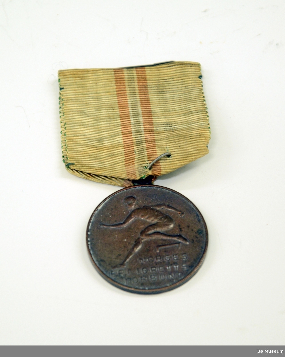 Medalje med innskrift:
NORGES FRI-IDRETTS FORBUND
Bånd i hvitt, med det norske flaggets farger i en stripe - svært falmet og gulnet.