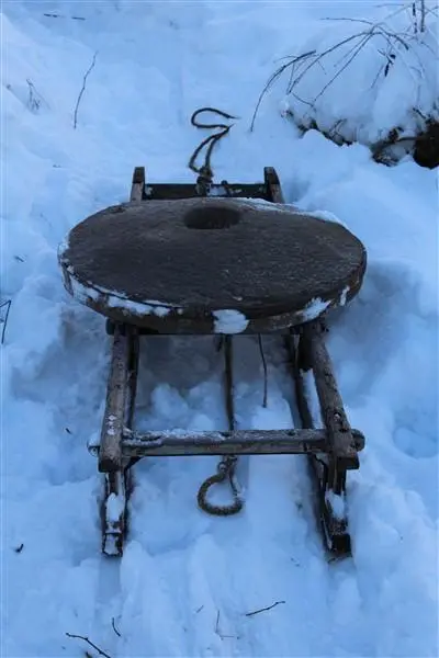 Kvernsteinen flyttes på en liten slede i snøen.