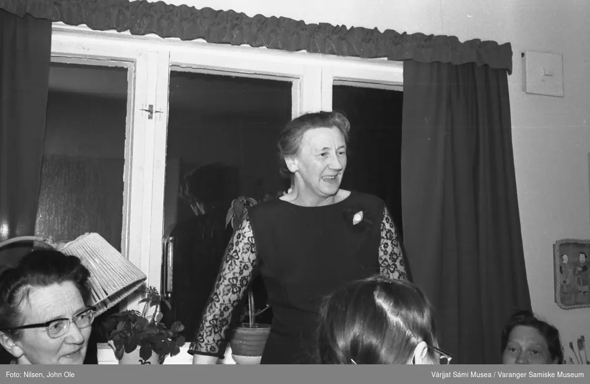 Bursdagsselskap, i anledning Signe Nilsens 50-årsdag, hjemme hos Signe og John Ole Nilsen i Bunes. Fra venstre Agnes Øwre, stående Magnhild Sivertsen som holder tale for søstra si Signe som sitter med ryggen til. 10. april 1967.