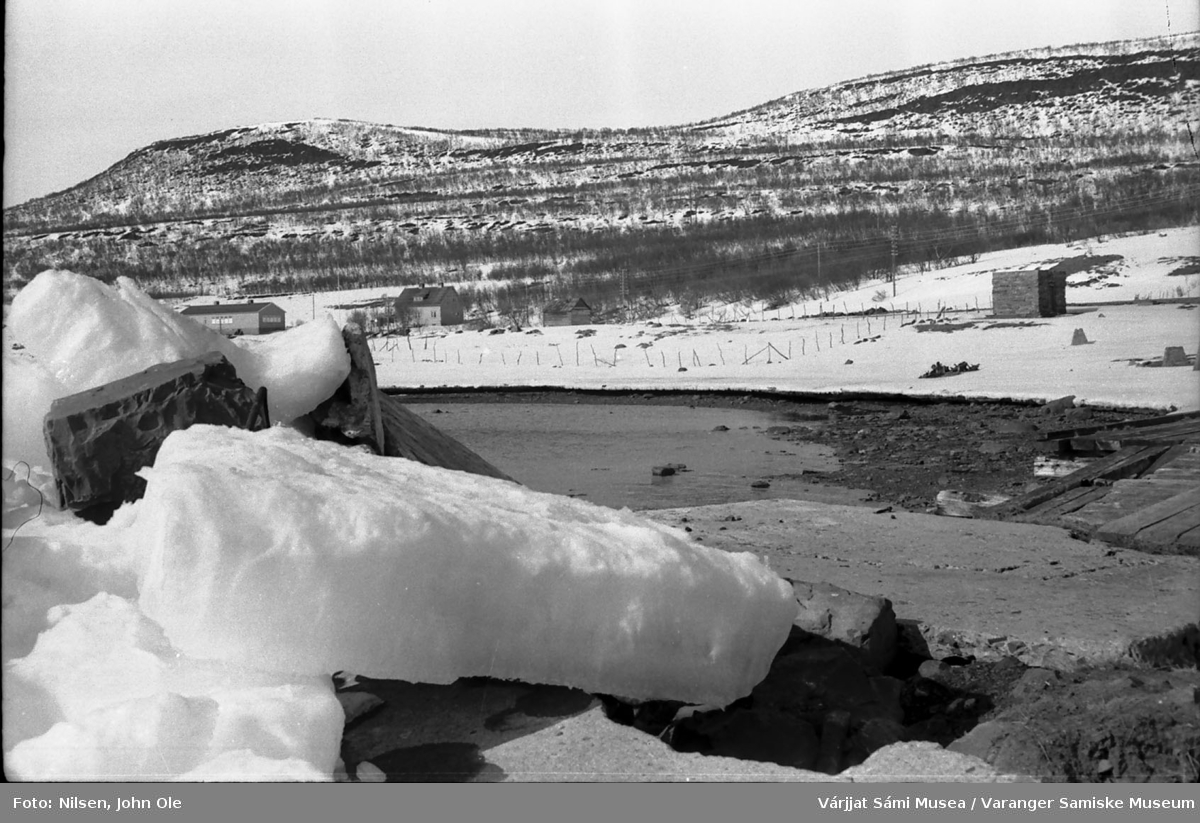 Kaia i Gornitak som er delvis brutt i stykker av fjordisen. Gamle Meskelv skole og lærerbolig med Aldon og Gornitakfjellet i bakgrunnen. 1967
