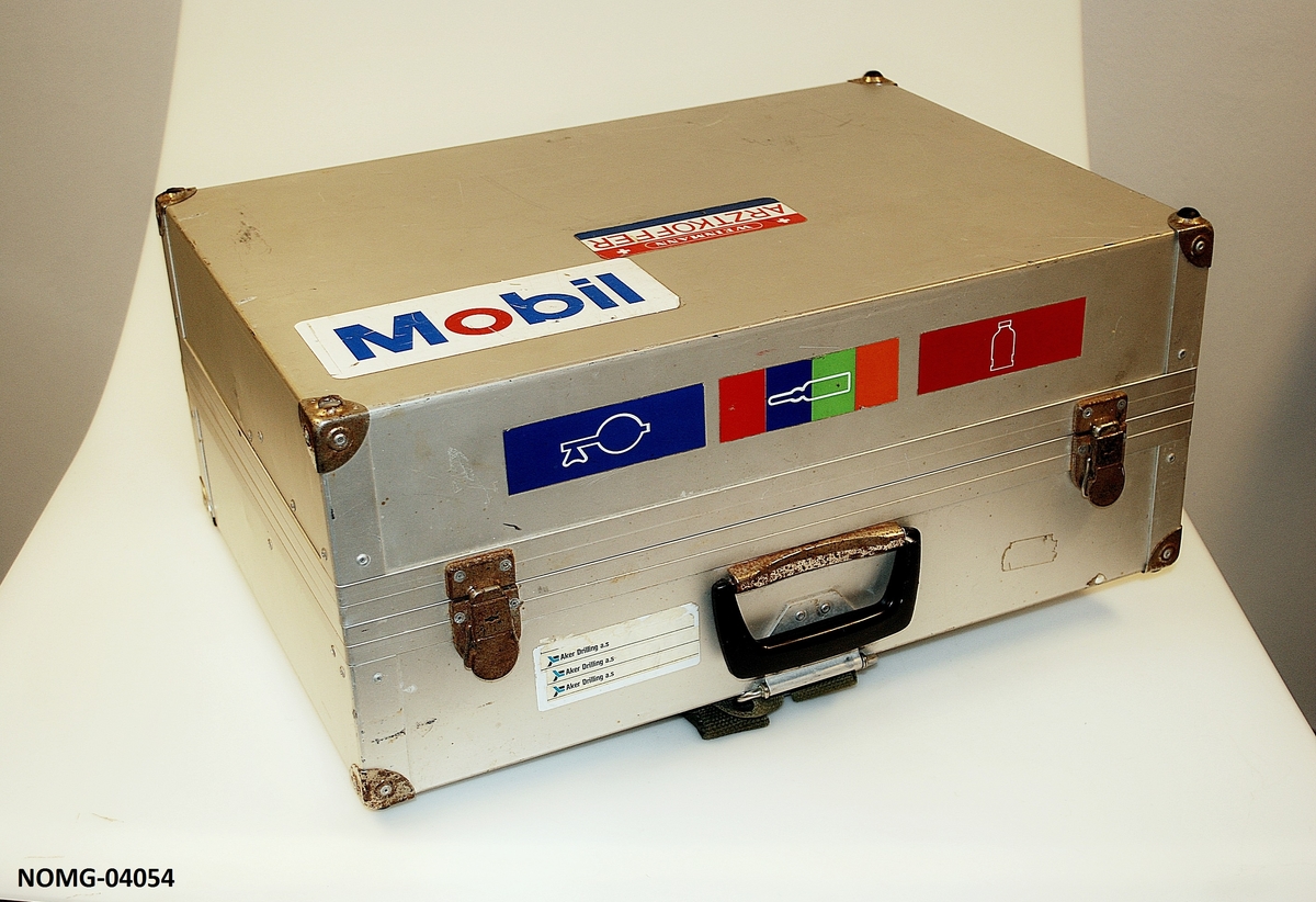 Legekoffert med hank og lås. Skulderrem på den ene siden. Tre rom inni med diverse medisinske utstyr.