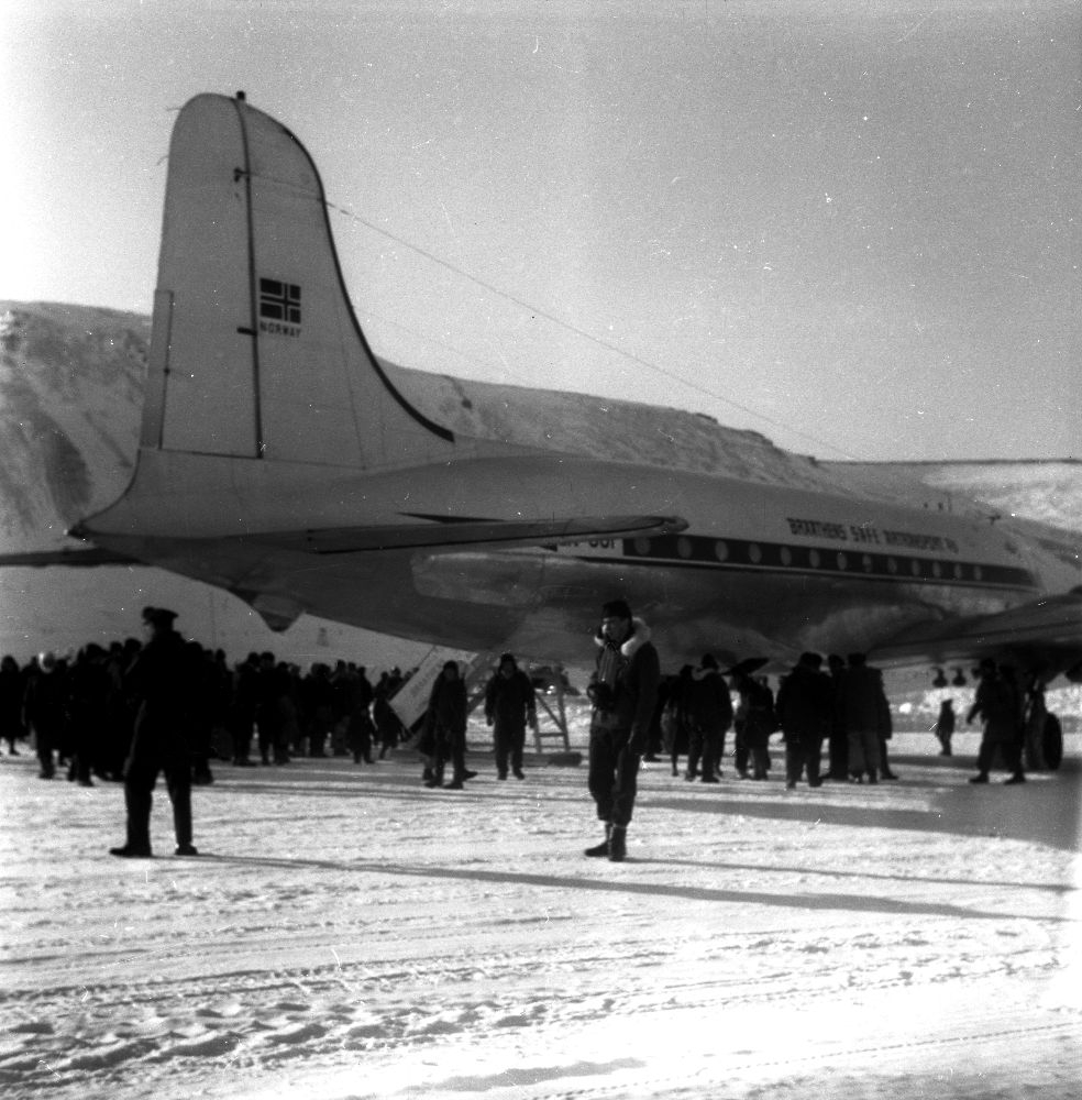 Lufthavn/Flyplass. Adventdalen/Svalbard. Et fly, LN-SUP, Douglas C-54B, Skymaster fra Braathens SAFE, har landet. Mange mennesker samlet rundt flyet.