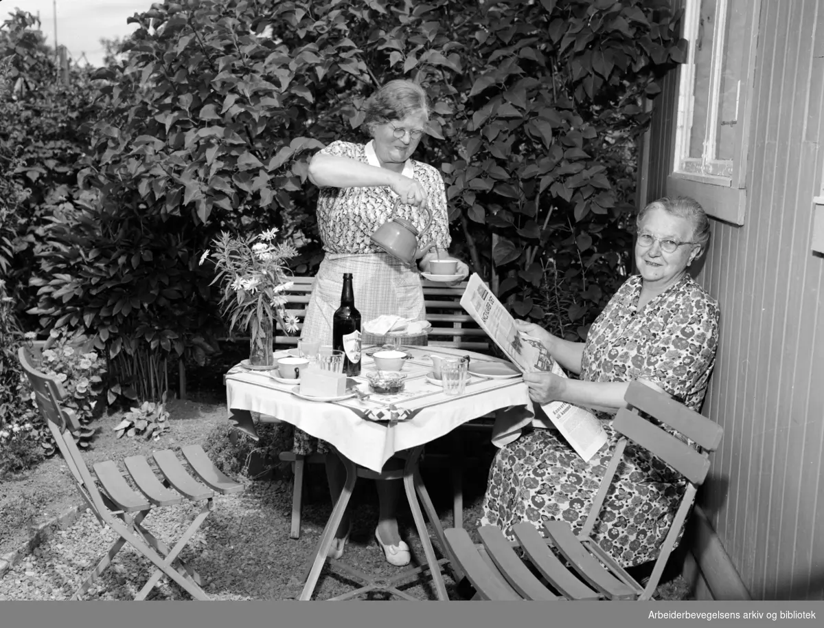 Severine Nilsen, eier av hytta Skogheim i Hjemmets Kolonihave på Bjølsen, serverer kaffe til Anna Skovli. .Juli 1954