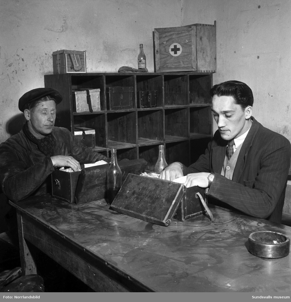 Lunchrum vid Östrands pappersbruk. Två män sitter vid ett bord med sina unikaboxar.