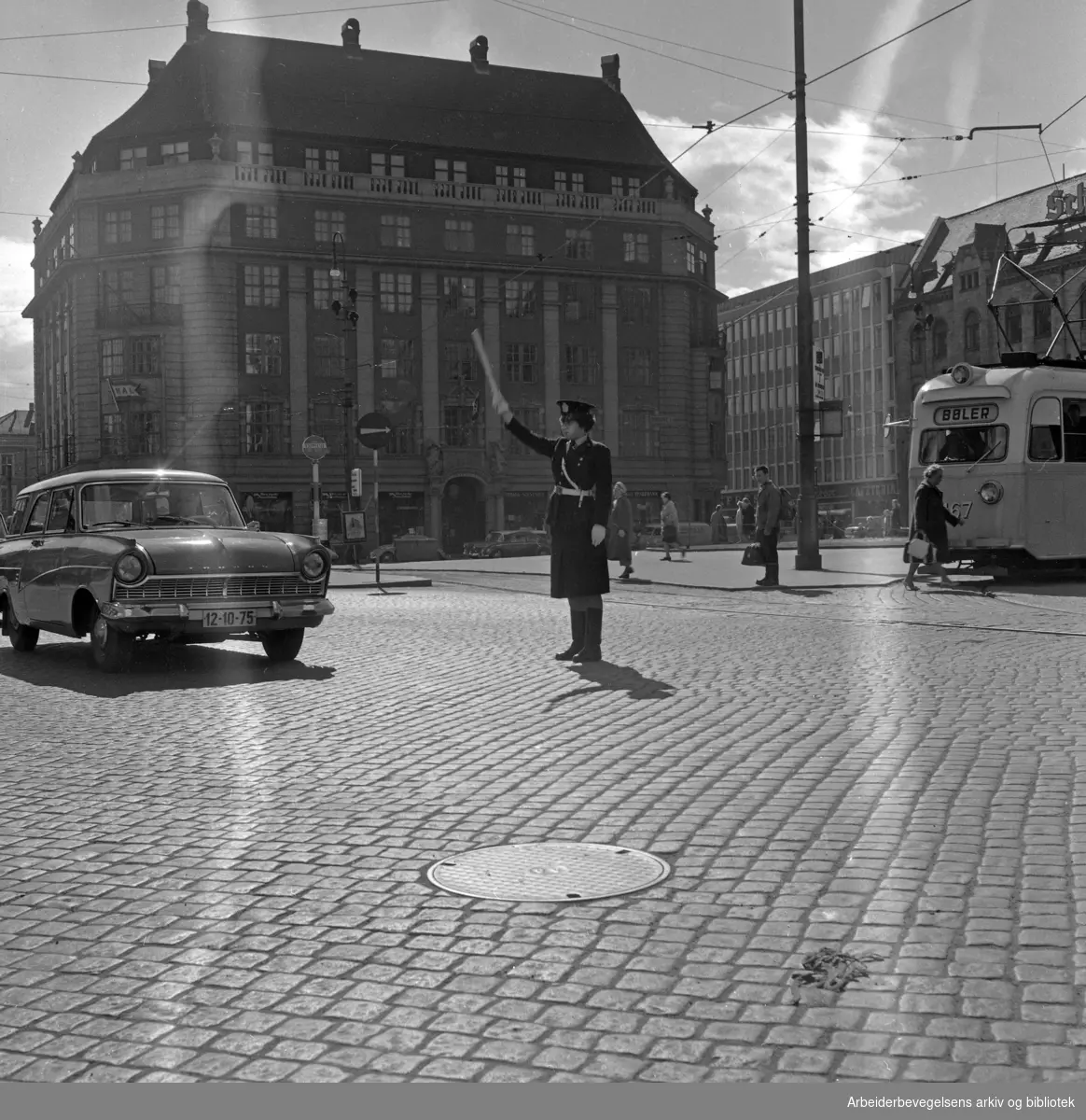 Kvinnelig politikonstabel dirigerer trafikk på Jernbanetorget. Første halvdel av 1960-tallet.