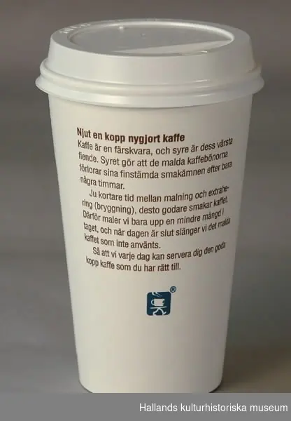 Engångsmugg av papp, vit med brun text. Lock av plast. Text: "Coffee cup".