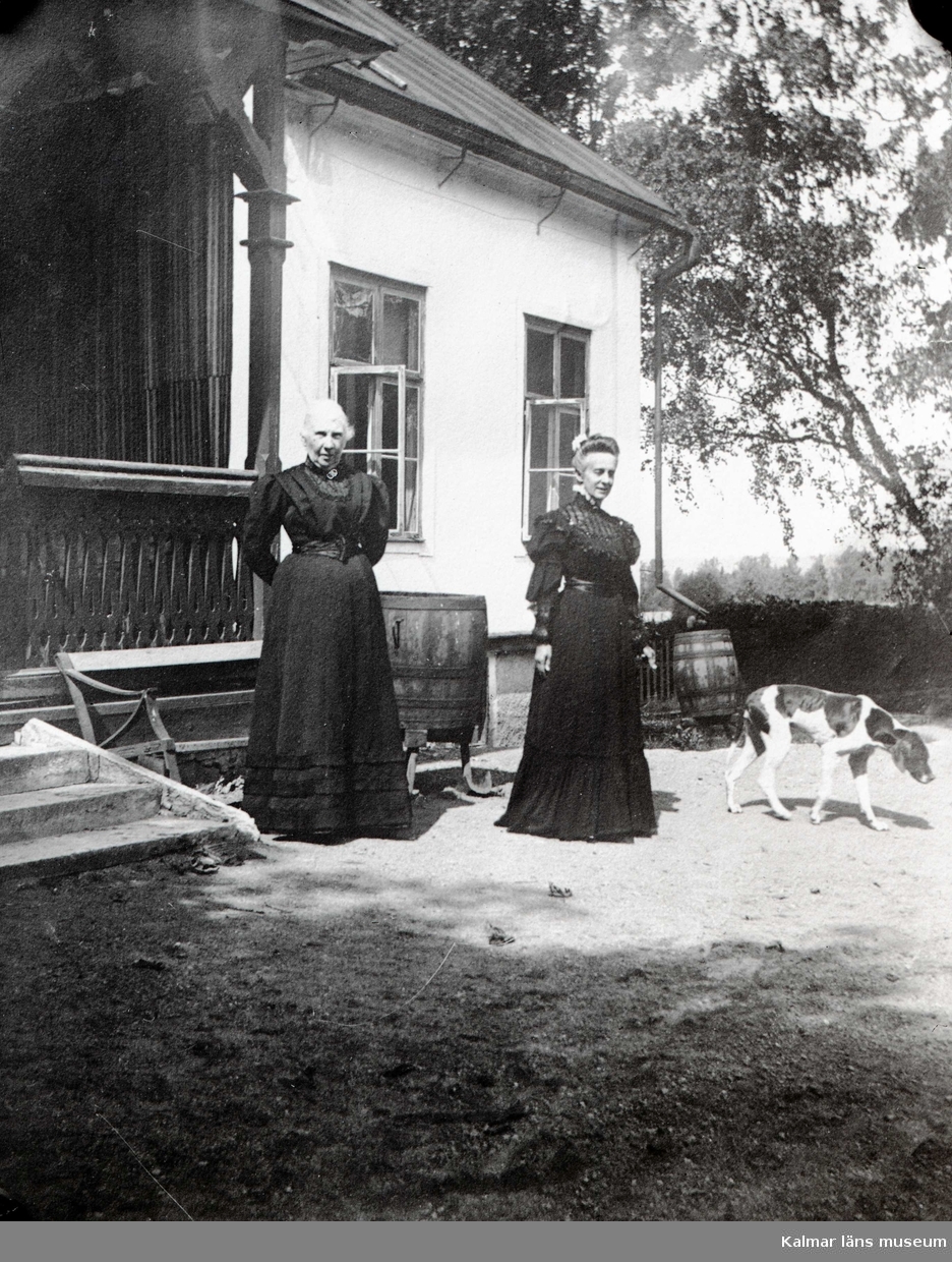 Två kvinnor vid trappa utanför hus.