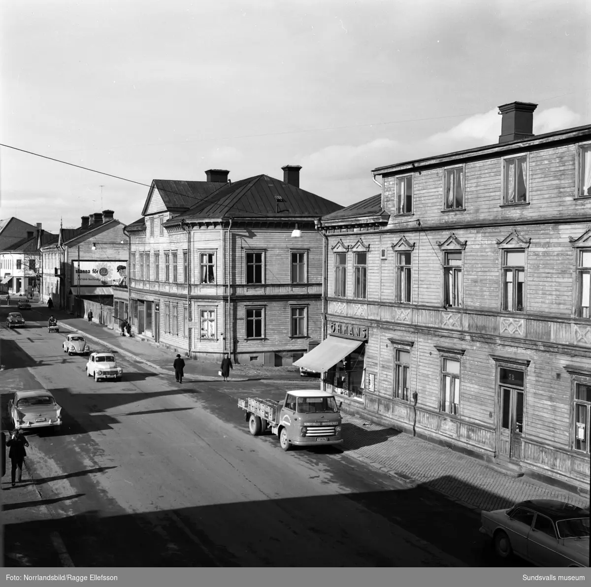 De gamla trähusen vid Storgatan 56-58 innan de revs. Frisörsalong, Öhmans livs, konsumbutik.