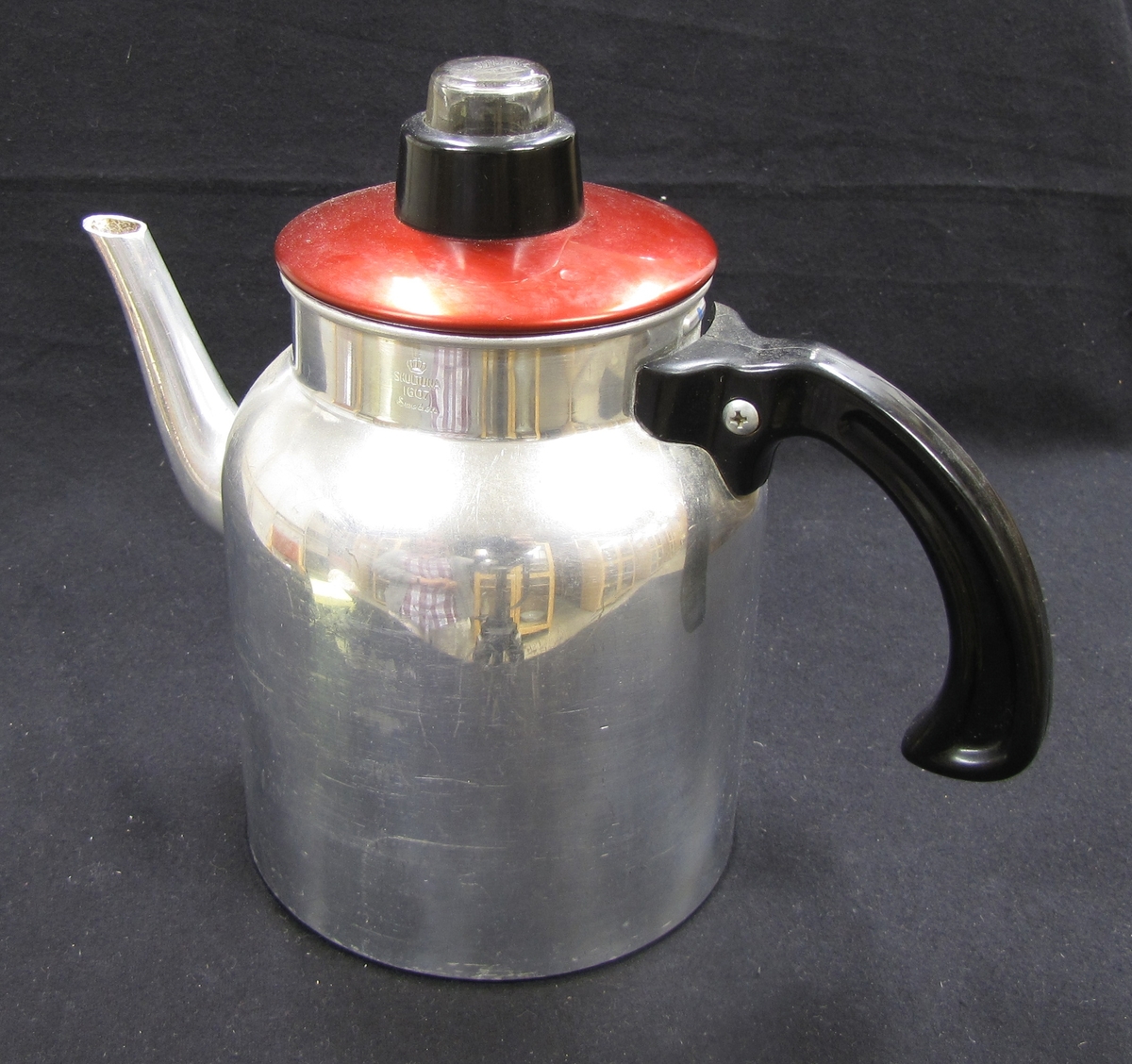 Kaffebryggarna har insatser för kaffepulver och filtrering. Rött lock med glasknopp.

Föremålen ingår i en samling från 1950 och 1960-talet. som använts vid olika skolkök i Trollhättans kommun. Föremålen utrangerades på 1980-talet och skänktes till Länsmuseet.