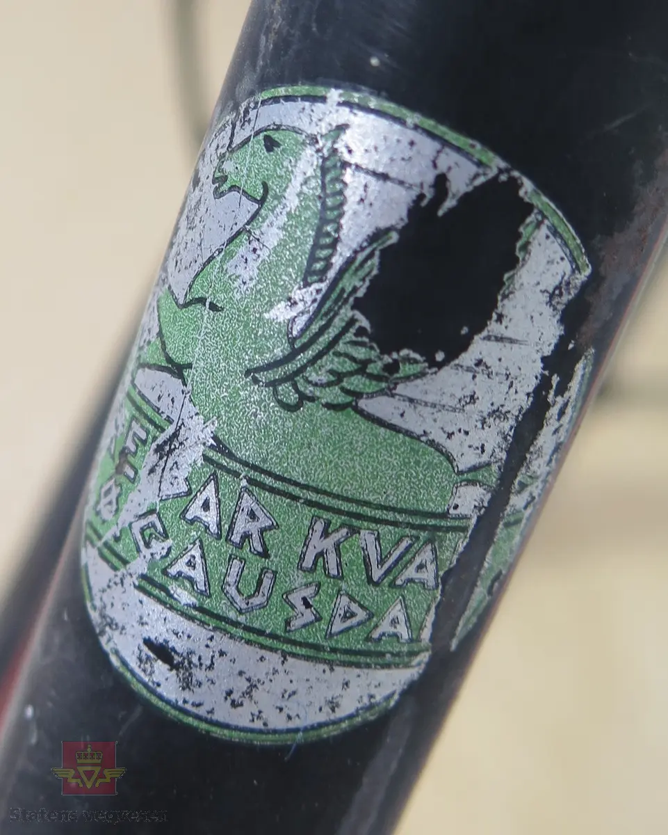 Tråsykkel, damemodell. Har to hjul, styre, sete, pedaler, frontlykt, ringeklokke, bagasjebrett, dynamo og refleks bak. Svart med rød staffering. Brunt sete og røde holker på styret. Sykkelen er i hovedsak lagd av metall, gummi og skinn.
Emblem med teksten: REIDAR KVAM Ø. GAUSDAL MIL.