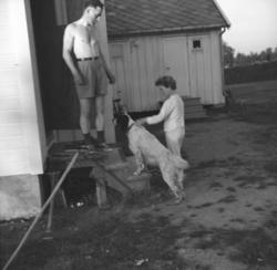 OLav Gabrielsen står på trappa og Turid og en hund står like