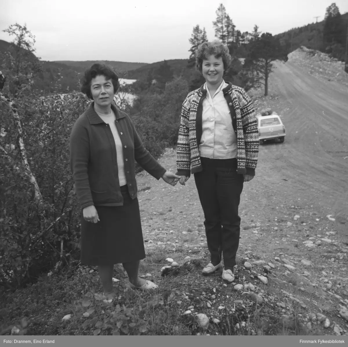 Jenny Drannem og Turid Karikoski står ved en grusvei. Bildet er muligens tatt i Neiden i Sør-Varanger.