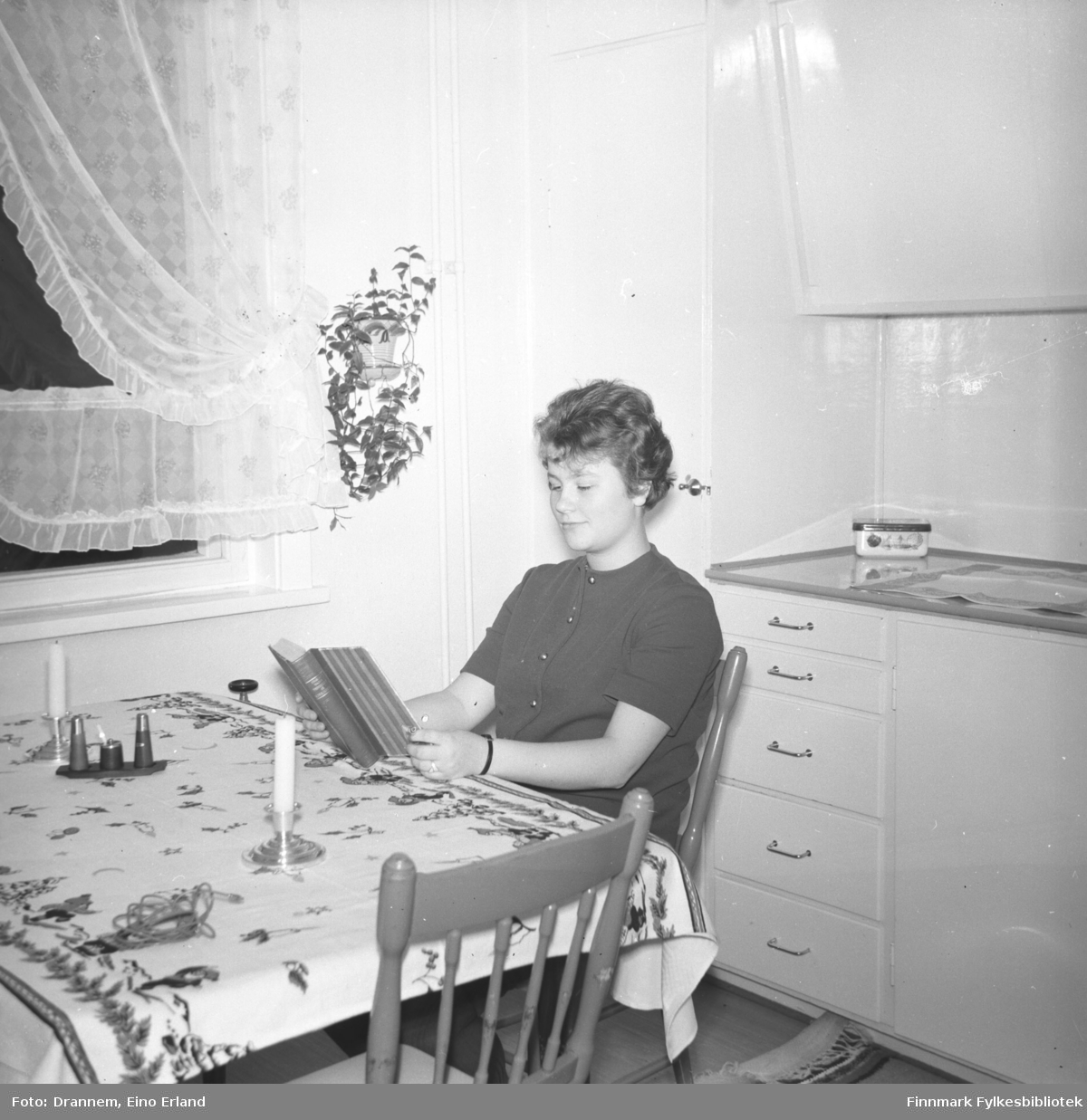 Turid Karikoski sitter og leser ved kjøkkenbordet hjemme i Hammerfest.