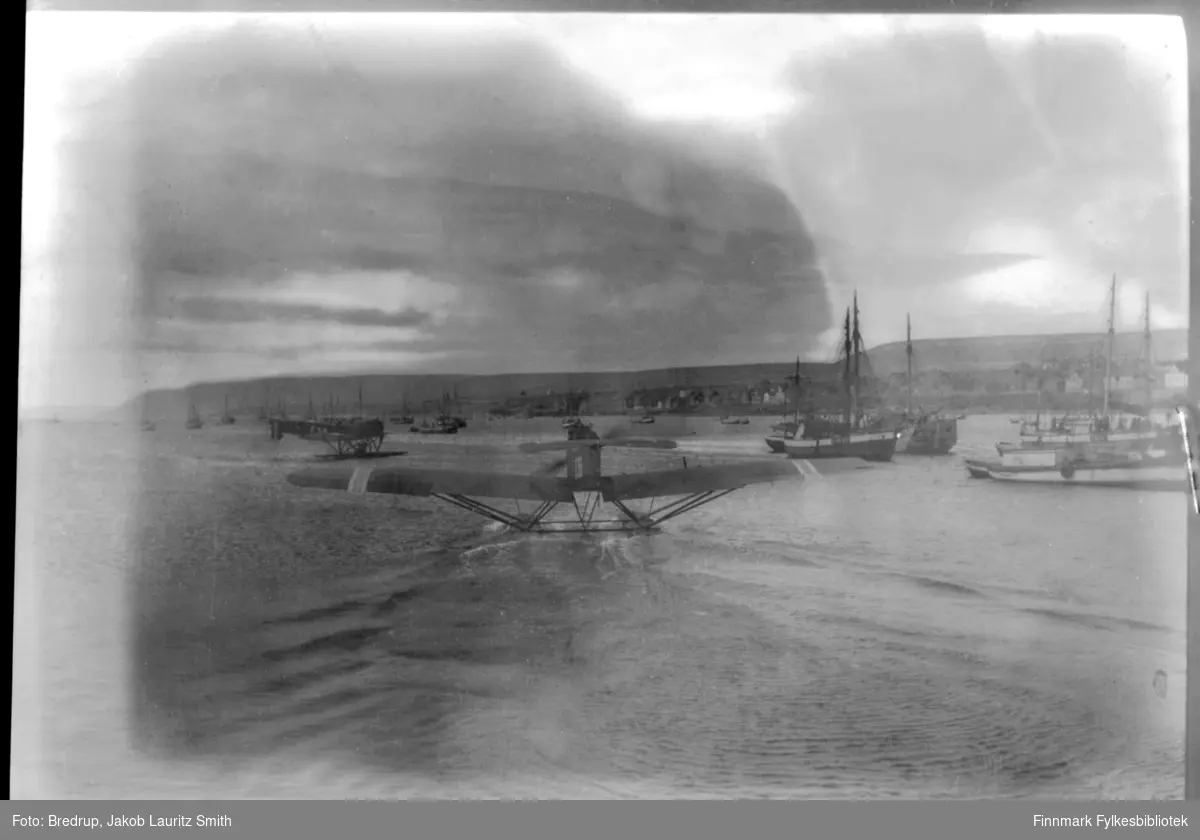 To fly av typen Hansa Brandenburg W.33 på havna i Vadsø. Ved svært stor forstørring framstår merkene på flyene som F 58 på det som er lengst fra kamera, og F 56 på flyet nærmest kamera. Disse flyene fløy fra Horten til Kirkenes på 21 timer, kom til Kirkenes 14.7.1922 - en slags pionerflyvning. I Kirkenes ble flyene reparert før ferden gikk videre 19.7. Turen fra Kirkenes til Vadsø tok 17 minutter, både ved start og landing tok de et par runder over byen. Masse folk hadde møtt fram, hurrarop lød fra Ørtangen. Flyverne var på mottakelse hos Fylkesmannen i ca. 1 time før ferden gikk videre til Hammerfest. Her deltok flyene i den første ambulanseflyvningen i norsk historie. Det var en tyfusepidemi i Alta og distriktslegen var blitt syk. F 56 og F 58 fløy legen fra Hammerfest til Alta, og videre til Stjernøya, der epidemien var særlig alvorlig. Flygerne var løytnantene L . - tzow Holm i F 58 og Hjalmar Riiser-Larsen i F 56. Mekanikerne het Engeland og Myhre.