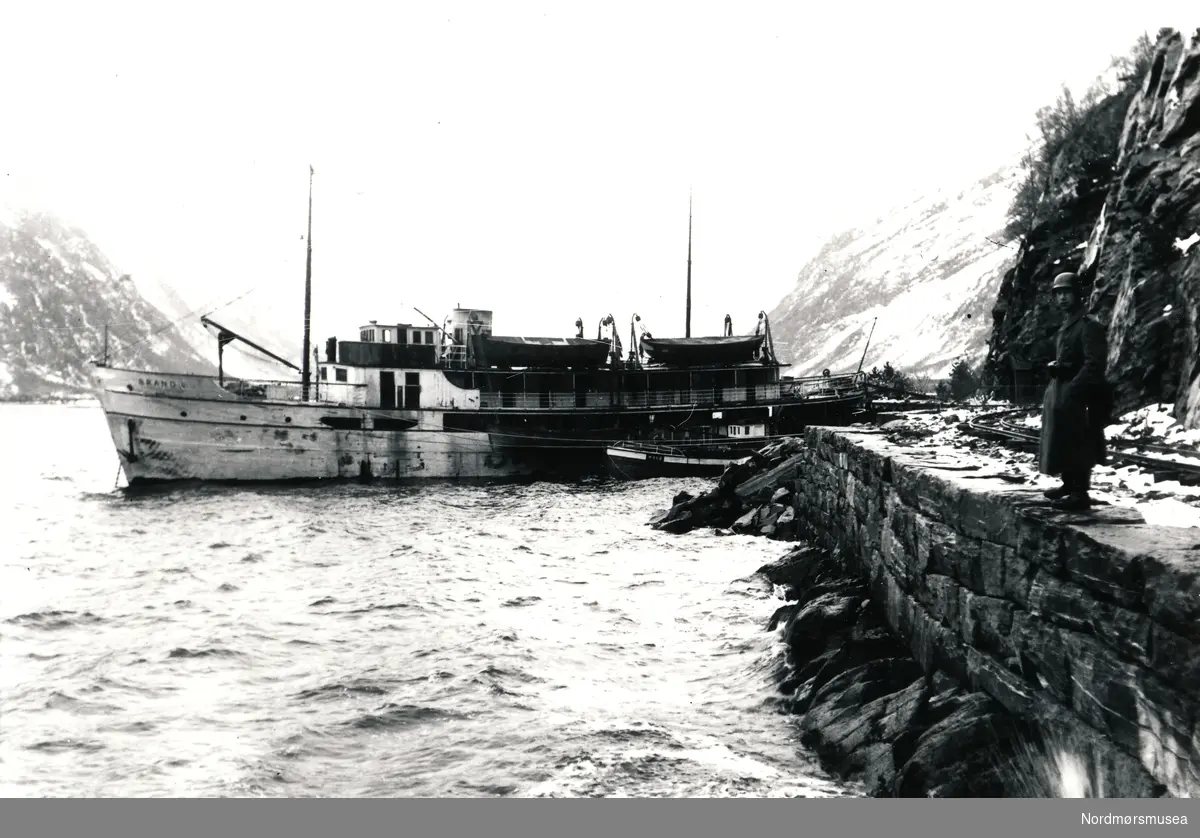 Båt som ligger til kai ved Hammarkaia. En tysk soldat står på kaia ved jernbaneskinnene.