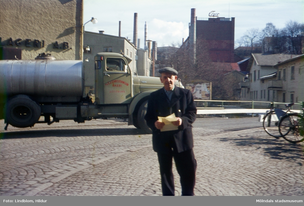 En man fotograferad framför en tankbil vid Forsebron i Mölndal, 1960-tal. I bakgrunden till vänster ses del av gaveln till huset Kvarnbygatan 6, byggnad tillhörande SOAB. I mitten ses Stora Götafors och till höger Götaforsliden 1-5.

För mer information om bilden se under tilläggsinformation.