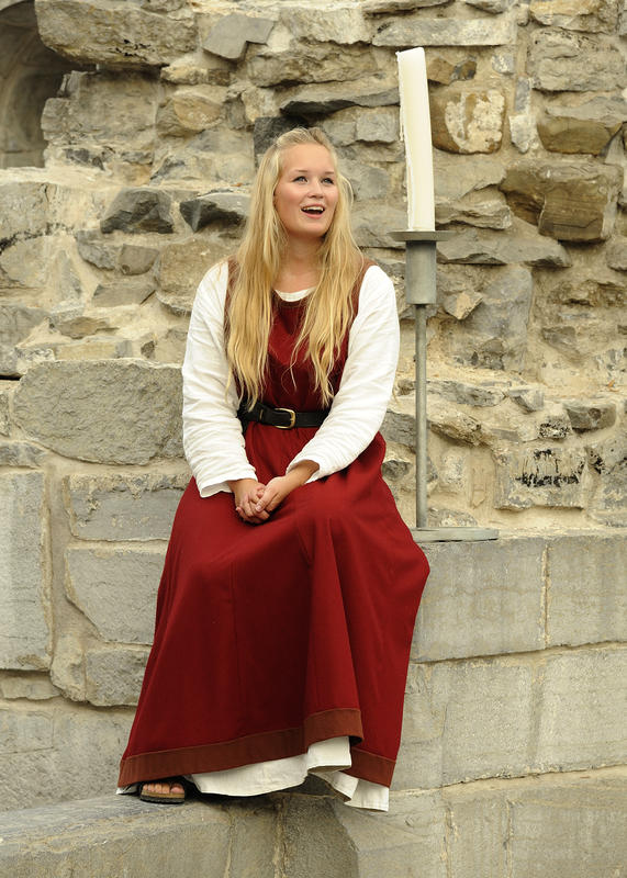 Singing guide, wearing medieval dress, sitting in the medieval ruins at Domirkeodden.