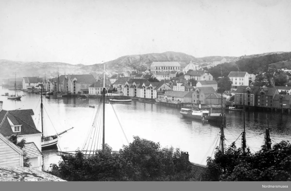 Bildet av Marcussundet og med bebyggelsen på Nordlandet i bakgrunnen, fotografert fra Innlandet - som vi ser litt av helt i front. Fra Nordmøre Museums fotosamlinger.