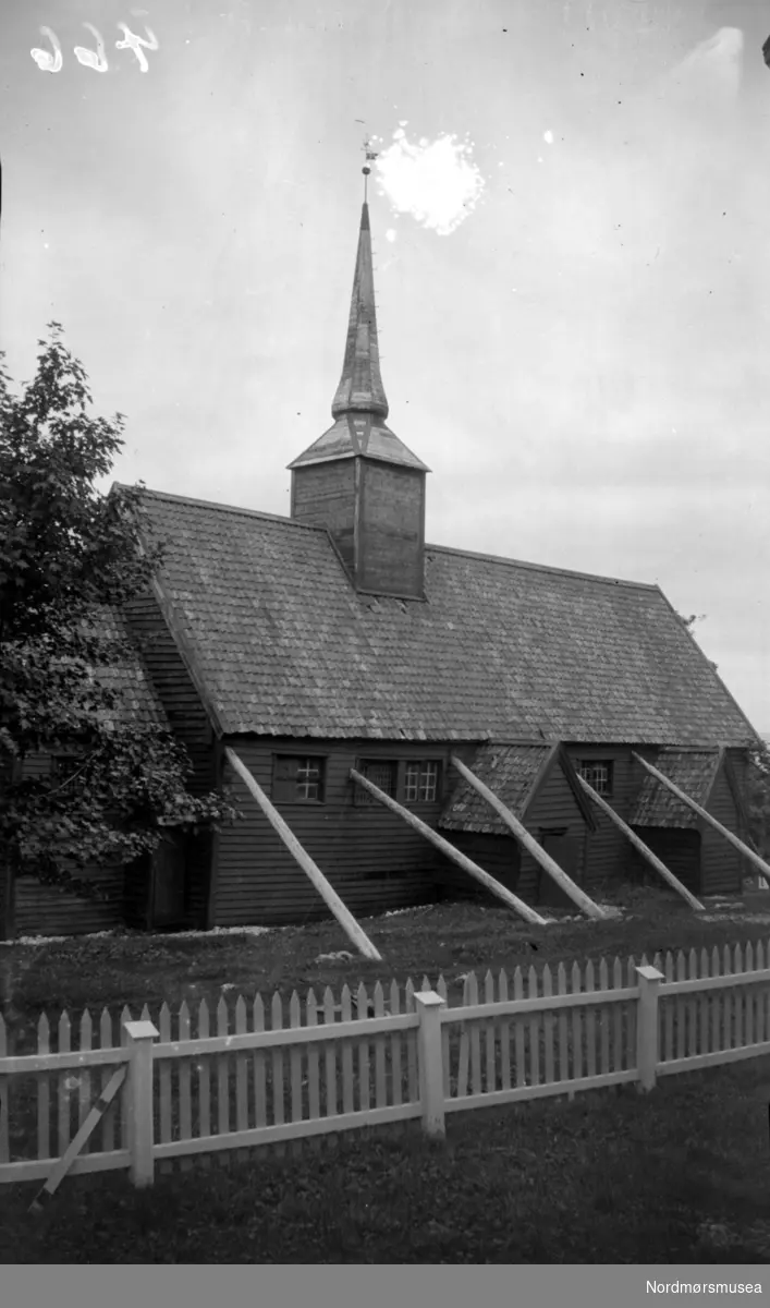 Kvernes stavkirke på Averøy, sett fra sør. Et stakittgjerde i forgrunn. Bildet er datert 1925. Nordmøre Museums samling