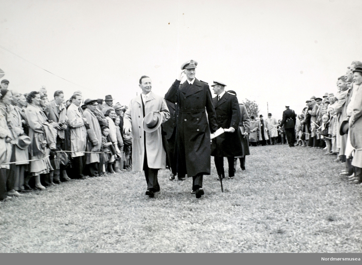 Tusenårsjubileet 1955 for slaget ved Rastarkalv i år 955 på Frei.  Her ser vi Kong Haakon kommer sammen med ordfører Axel Fiske og Kronprins Olav med følge.  Kongen hilser de fremmøtte. serie.  (Fra Nordmøre Museum sin fotosamling.)