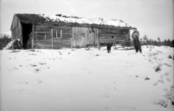 Vinterbilde av et eldre gårdshus, trolig med Kate Fasting og