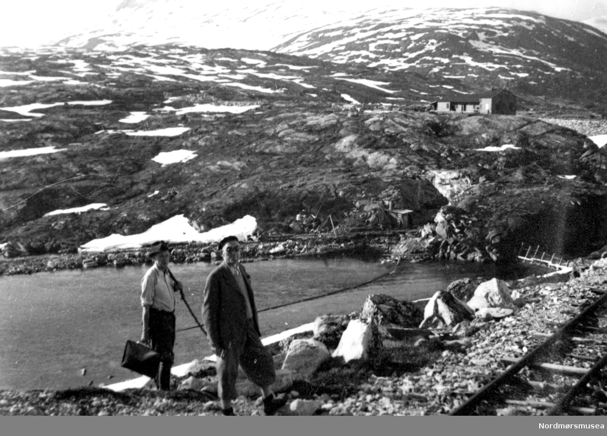 Ingeniører. Alpelue, solbriller, dokumentmappe i høgfjellet. Anleggsjernbane, hytte, Aura vasskraftutbygging 1941. Fra Nordmøre Museum sin fotosamling.