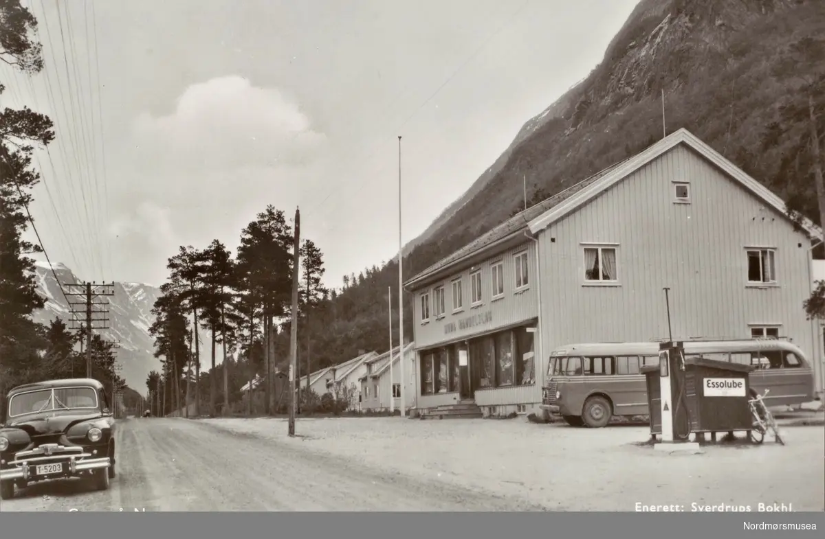 Postkort ";1043"; med motiv fra Grøa Handelslag som ligger ved veien på Grøa i Sunndal kommune. Her finner vi også en bensinstasjon. Vi ser også en bil med registreringsskilt ";T-5203";. Datering er usikker, men trolig fra perioden 1953 til 1955. Fra Nordmøre Museums fotosamlinger. /Reg:EFR2013/
