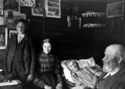 Foto av en eldre kvinne som ligger i en seng, omkranset av b