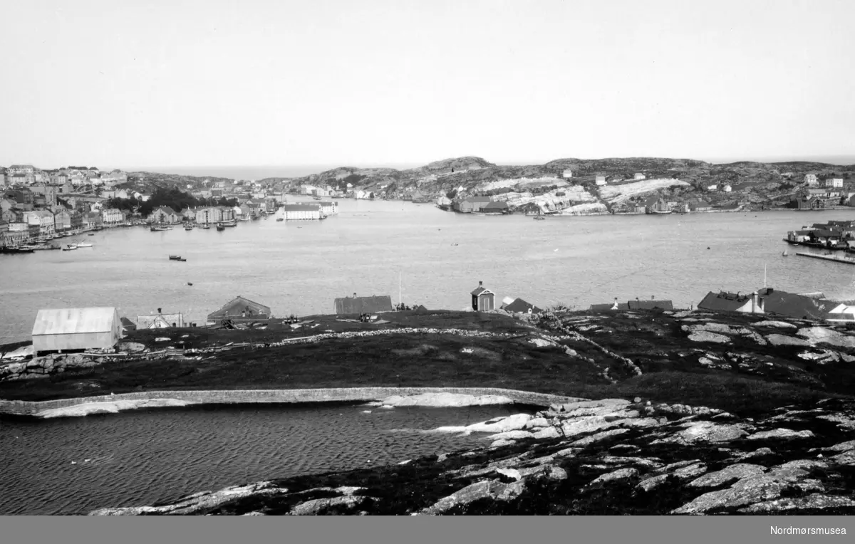 Foto fra Innlandet i Kristiansund, hvor vi ser deler av vannreservoaret - brannvass eller reinvassdammen - i front. På andre siden av havnebassenget finner vi ellers Kirkelandet til venstre, Gomalandet i midten, samt en liten flik av Nordlandet til høyre. Fra Nordmøre museums fotosamlinger.
