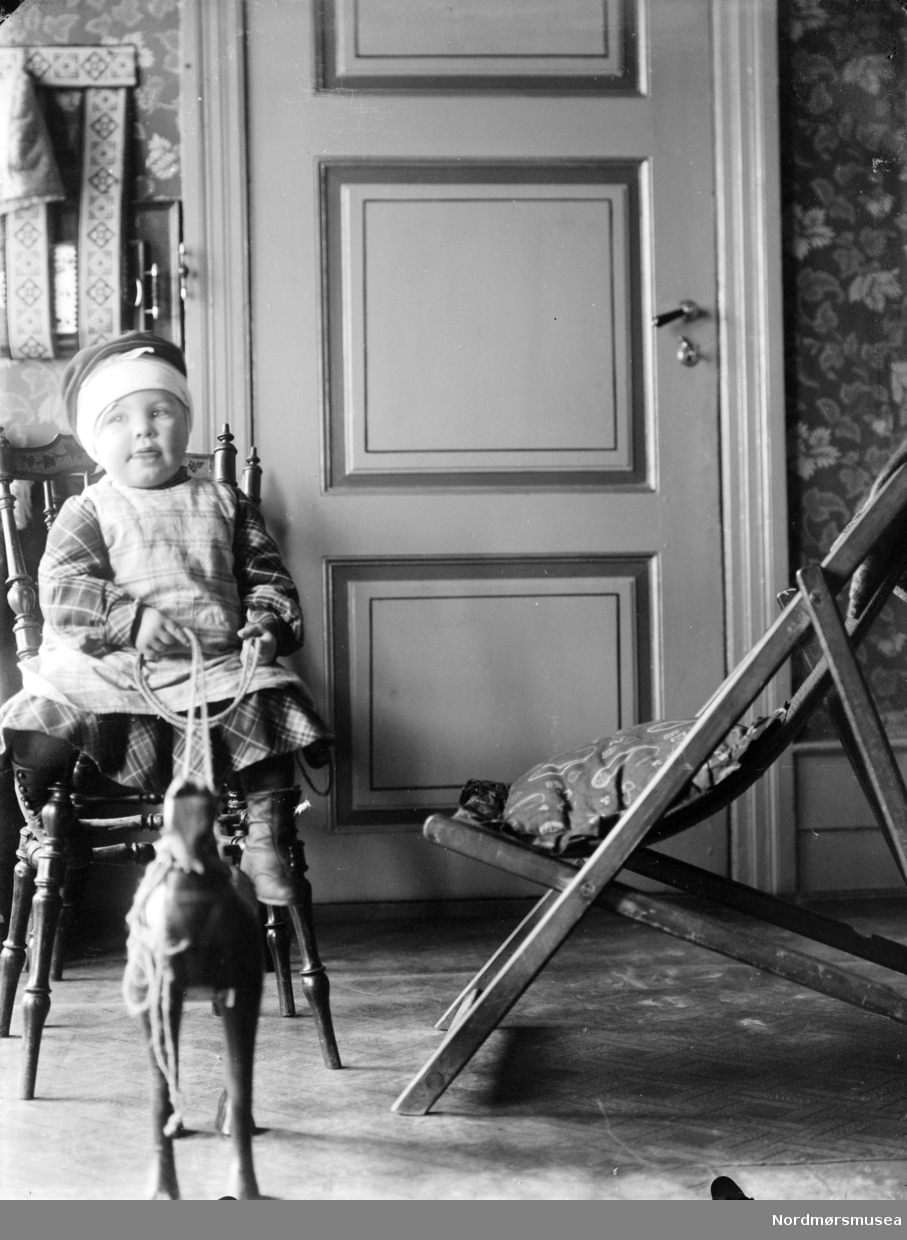 Foto av et barn som leker med en lekehest. Kan være fra Sverdrupfamilien/slekten, eventuelt fra deres bekjentskaper. Datering er ukjent, men trolig omkring 1920 til 1930. Fra Nordmøre museums fotosamlinger. EFR2015