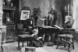 Arrangert gruppebilde i en atelier stuesalong. På bildet ser