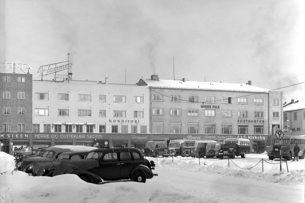 Østre Torg, Hamar. Parkering, biler, busser. Rutebilstasjonen. M.Steen, Musikkhandel, Brødr. Westgaard, Hamar Postkontor, vinter.