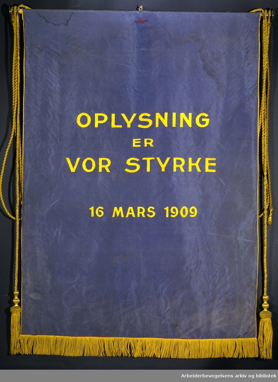 Oslo arbeidersamfunds kvinnegruppe..Bakside..Fanetekst: Oplysning er vor styrke.16 Mars 1909