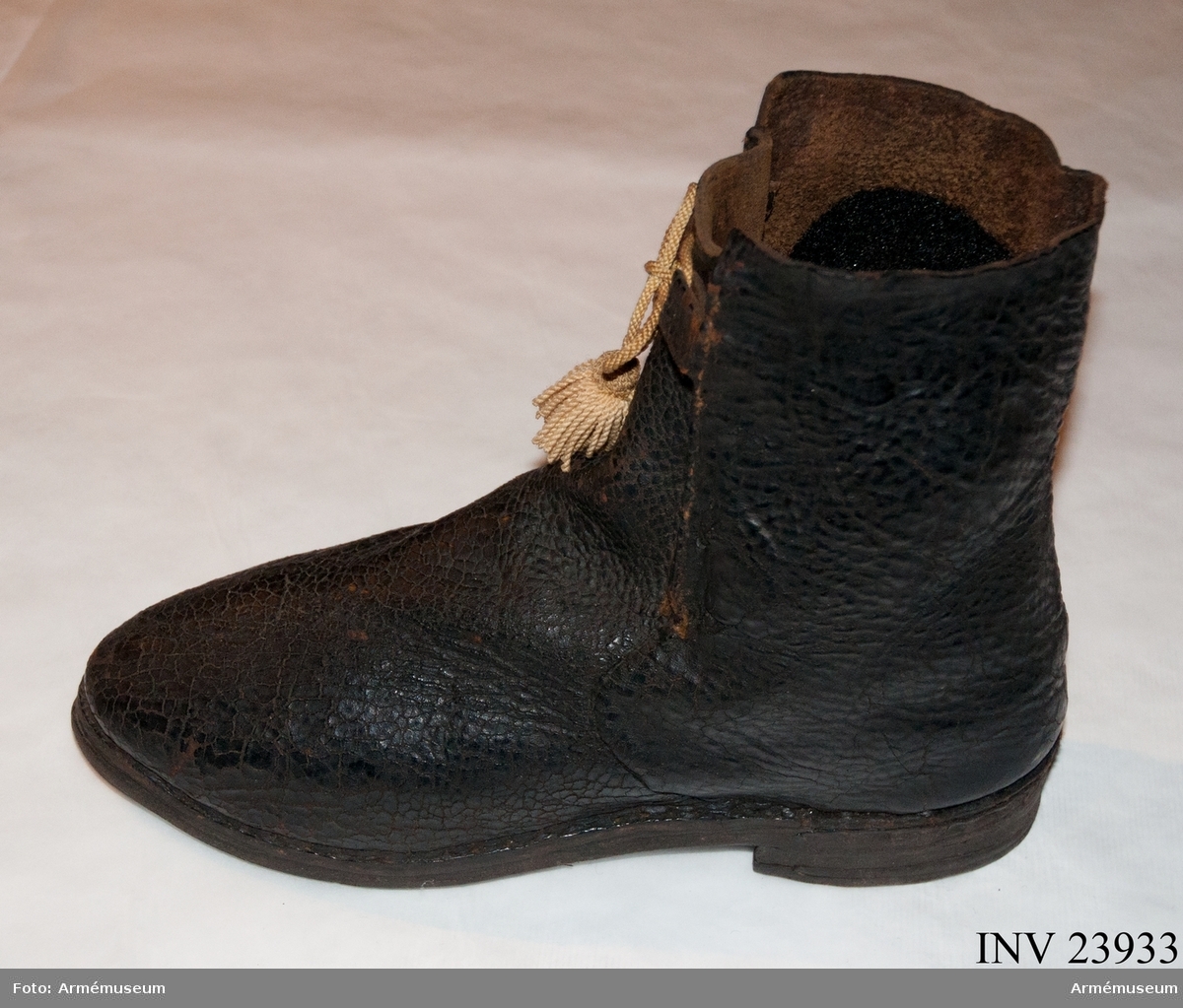 Känga av svart läder med snöre (senare tillägg). Det gula kängbandet på fotografier är AM.120193.