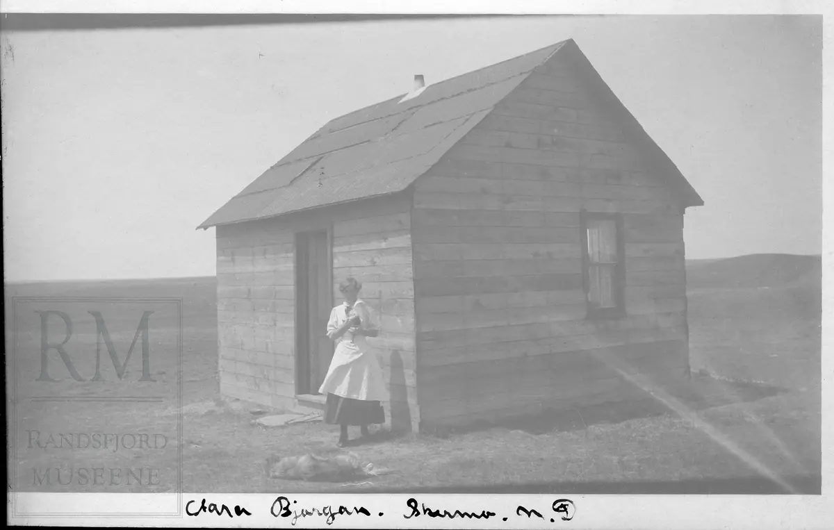 Ei dame står utenfor et hus på prærien i Nord-Dakota.