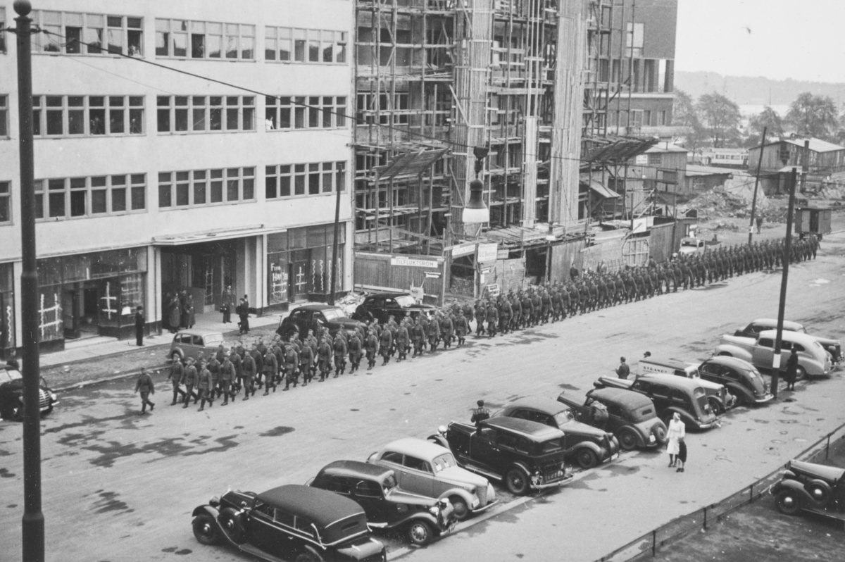 Tyske tropper marsjerer i Roald Amundsens gate. I bakgrunnen Solplassen og Oslo Rådhus under bygging.