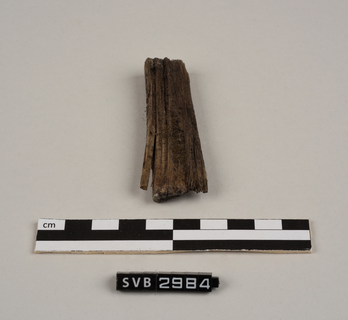 Tregjenstand med tilnærmet rundt tverrsnitt. Tremateriale er tørt og sprukkent. Det er 2 løse deler. Det er en lapp på undersiden med russiske tall og bokstaver.