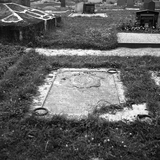 En gravsten med inhuggen text, järnringar och någon symbol.
Göteryd, gamla kyrkogården.