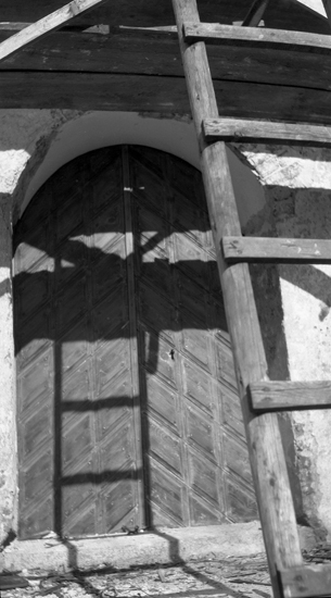Foto på en kyrka med närbild på dörren, med en stege som står lutad över.