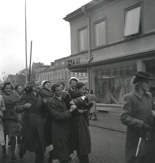 Andra dagens studenter, 1944.
En student bärs iväg längs Storgatan, från Stortorget. Till höger syns dåv. P.N. Perssons hörna, och i bakgrunden skymtar Stadshotellet.