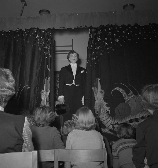 Sjuans fest , 10/2 1953. 
En flicka i frack uppträder inför publiken i Flickskolans gymnastiksal.