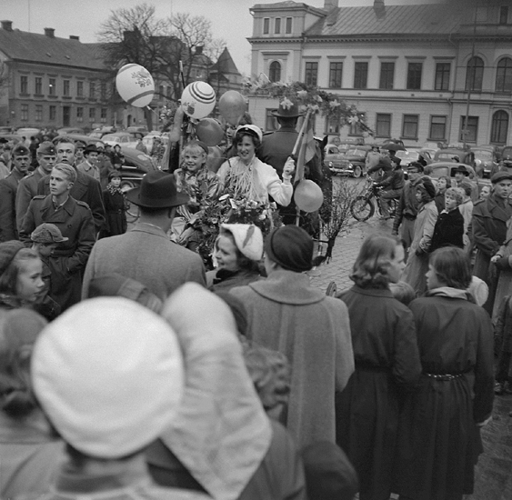 Studenterna andra dagen, 3/5 1955.
En kvinnlig student får skjuts i lövad kärra, från Stortorget. I bakgrunden syns 
bl a Stadshotellet och några av husen längs Kronobergsgatan.