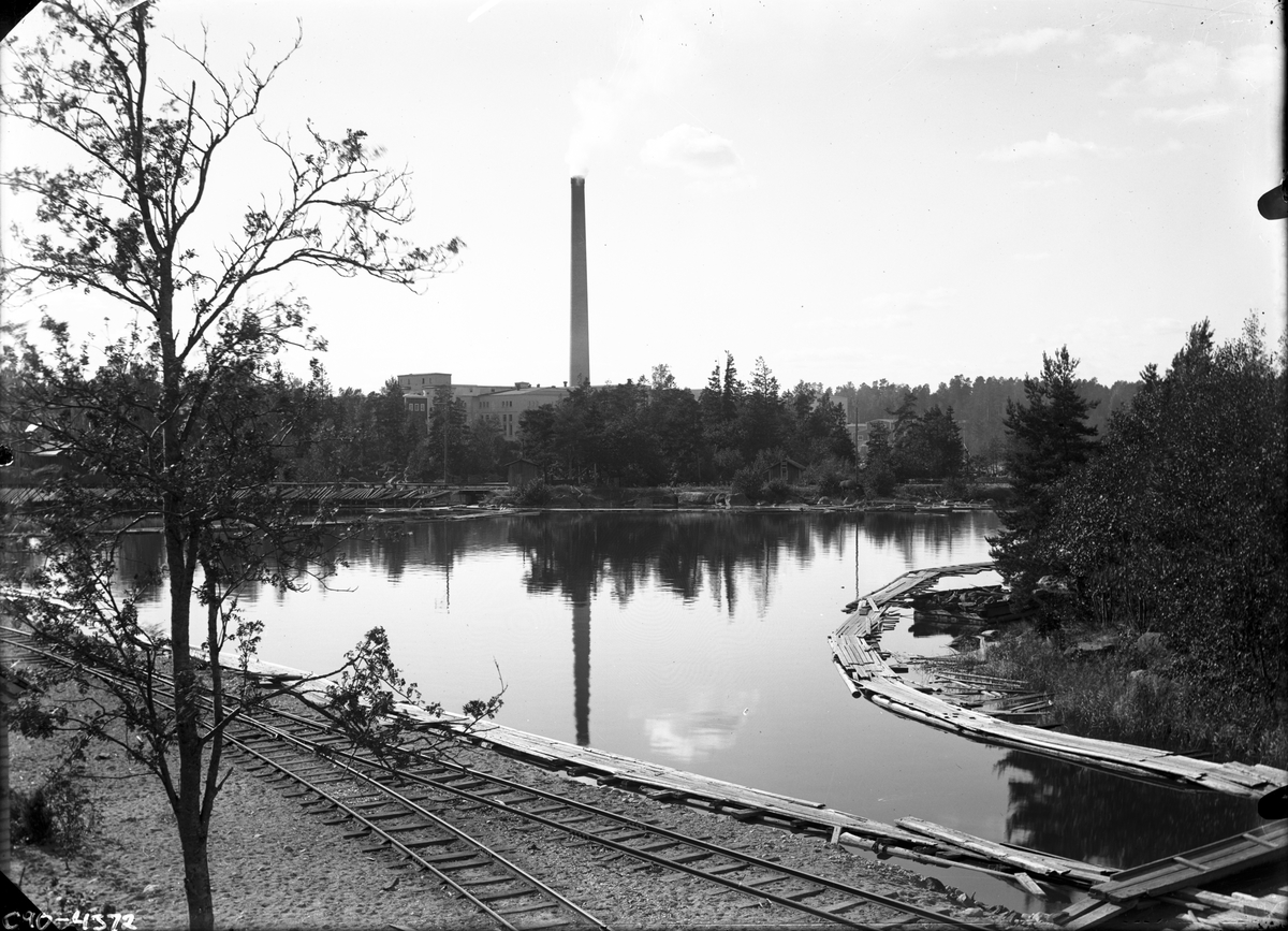 Järnvägsspår vid sjö och fabrik.