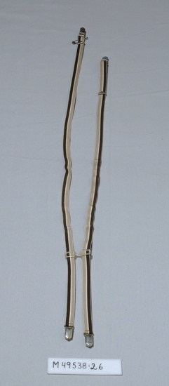 Randiga hängslen av elastiska band i färgerna; beige-vit-brun.
Bak ett plastspänne för att hålla ihop resårbanden.
Vita metallknäppen i kortändarna för fästning i byxorna med vita metallspännen

Inskrivet i huvudbok 2008-05-07