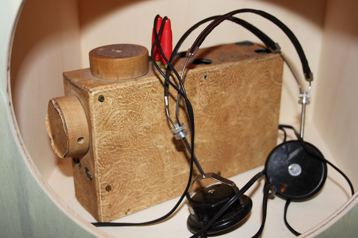 Radiomottaker, hjemmelaget. Rektangulært chassi laget i trefiner.. Med sorte høretelefoner med stempel OMEGA. Dette eksemplaret er fortsatt i utmerket stand. Det følger også med en improvisert antenne.