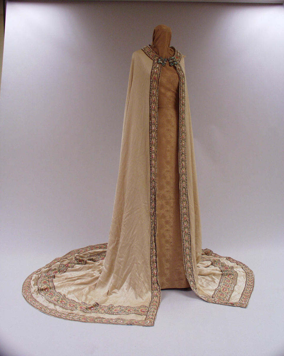 White cape with details of pearls and coloured tread. Long train.