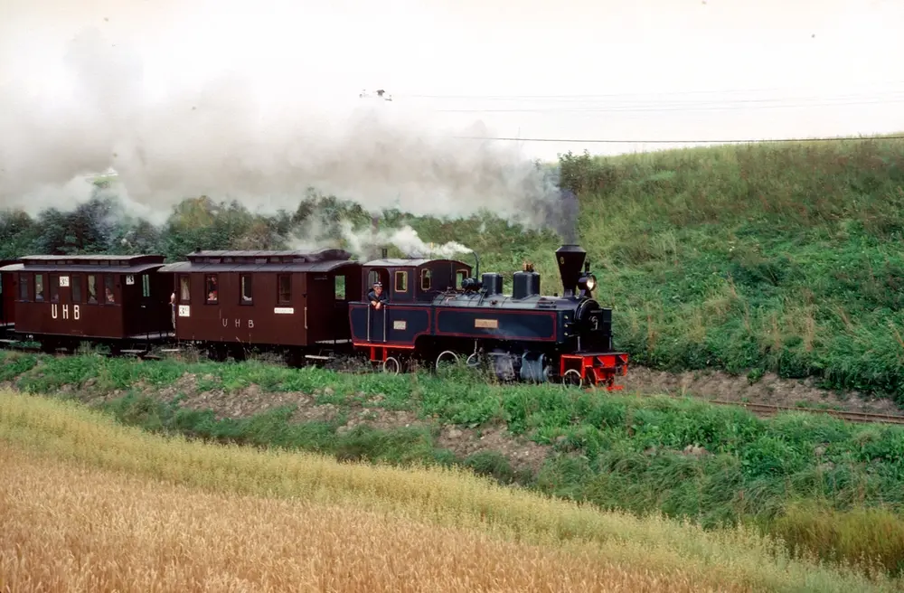 Lokomotivfører Finn Halling på damplokomotiv nr. 6 Høland med museumstog på Urskog-Hølandsbanen, Tertitten. Vi ser vognene CF11 og C12, to toakslede vogner anskaffet fra Polen til museumsbanen.